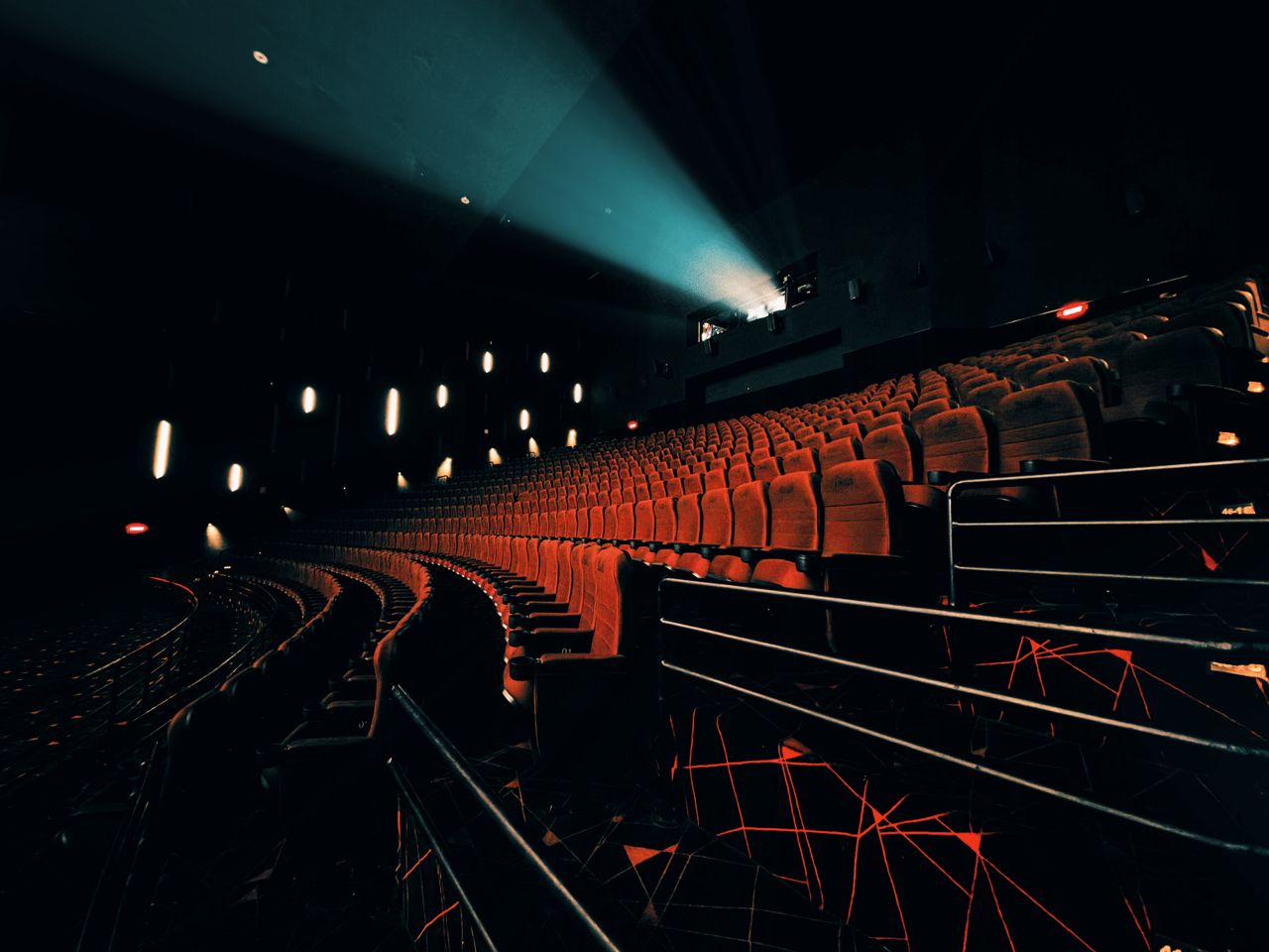 Dark, empty theater with dramatic seat lighting and projector beam.