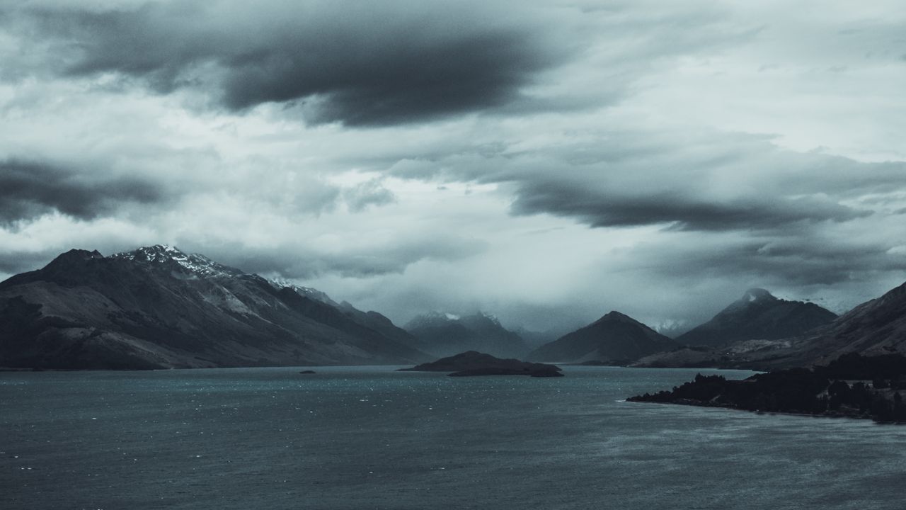 Mystical landscape with cloudy mountains over a serene lake, evoking a sense of calm and mystery.